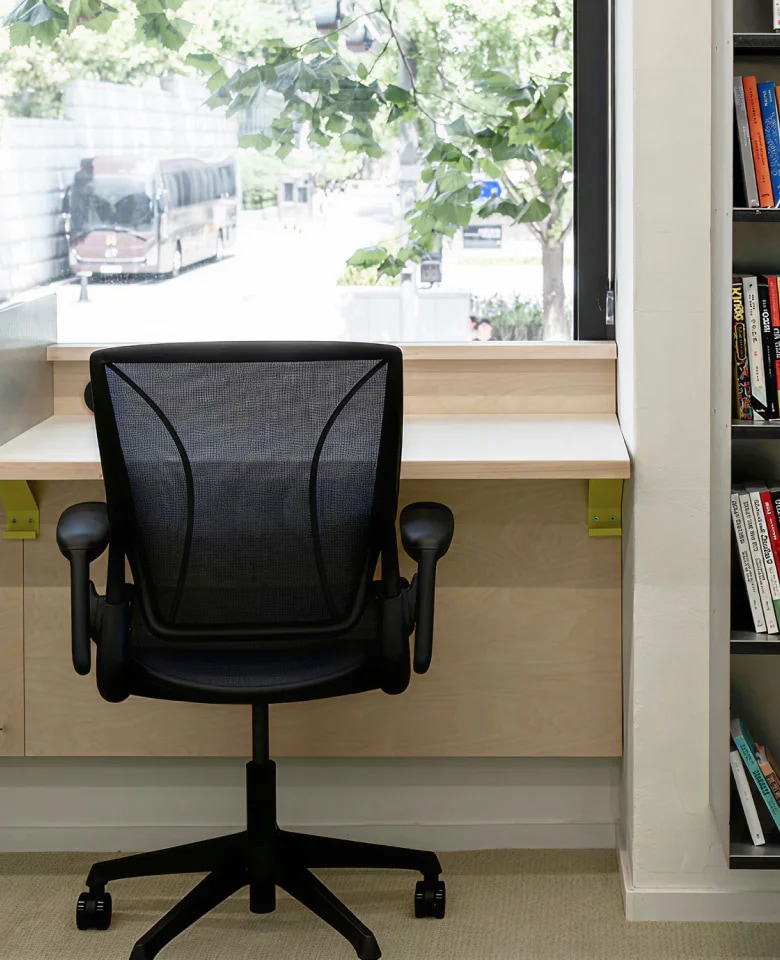 블랙 메쉬 소재의 World Chair가 우드 책상 앞에 배치된 서재 공간 이미지 