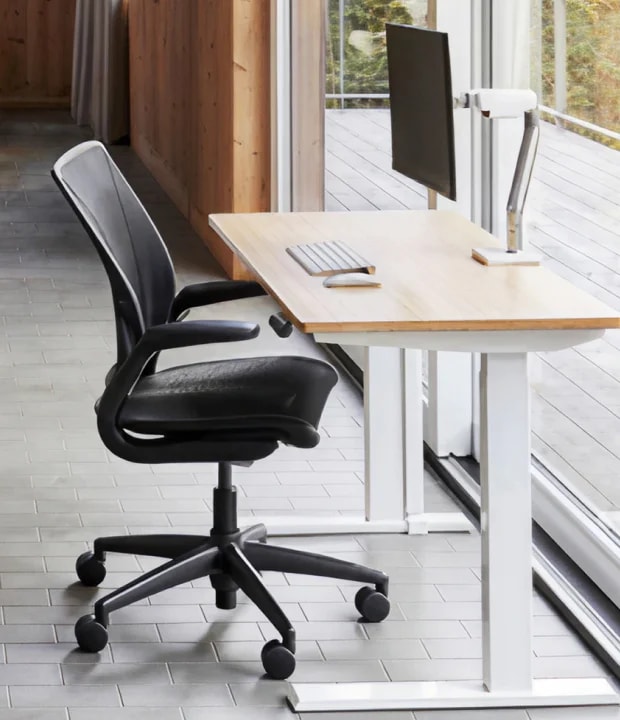 블랙 메쉬 소재 World Chair가 우드 책상 옆에 배치된 이미지 