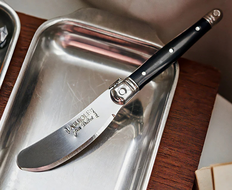 블랙 컬러 핸들의 Laguiole Butter Knife가 사각 실버 트레이 위에 놓인 이미지 