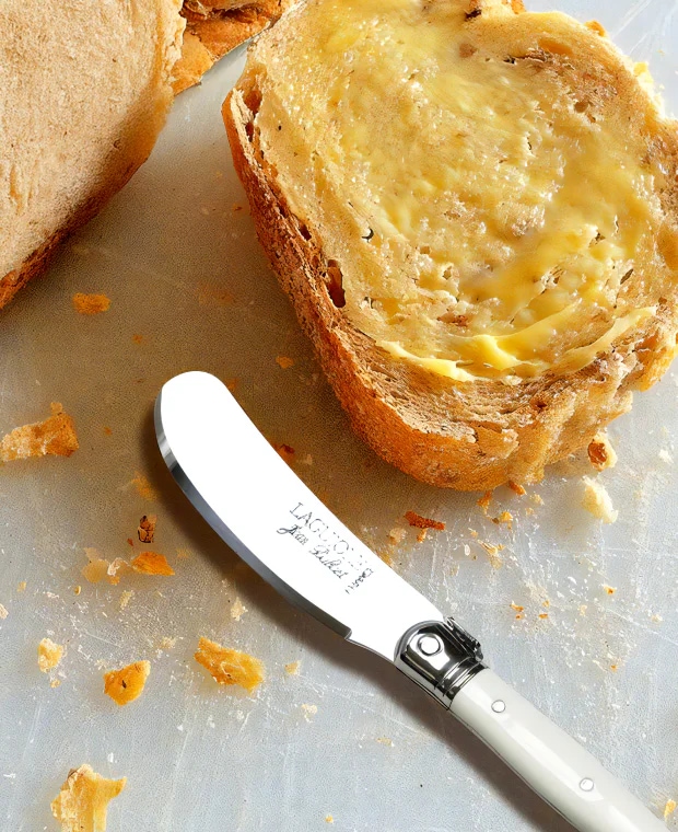 버터가 발라진 구운 빵 옆에 화이트 컬러 핸들의 Laguiole Butter Knife가 놓인 이미지 