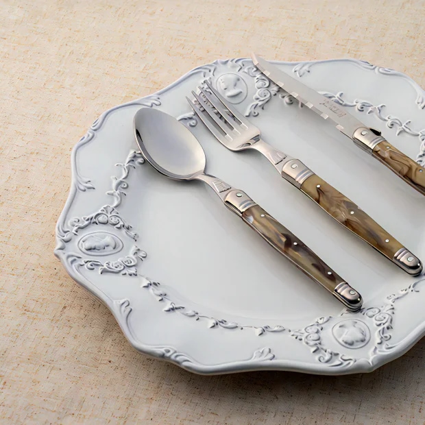 브라운 마블 패턴 핸들의 Laguiole Marble Cutlery Set가 화이트 플레이트 위에 놓인 이미지 